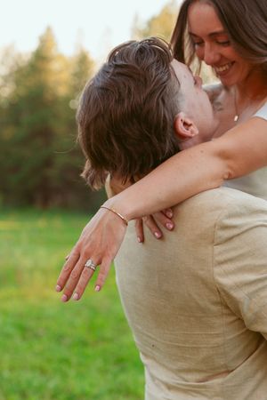 A tender moment is shared between newlyweds in formal attire embracing in a sunlit field.