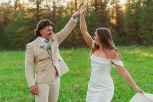 Joyful couple dances and celebrates in outdoor wedding setting with natural scenery.