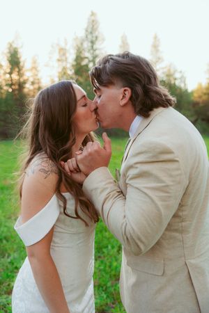 A tender romantic moment between newlyweds in a sunlit forest setting.