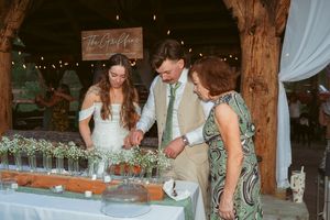 Newlyweds and guests gather around a rustic buffet table at an outdoor wedding reception.