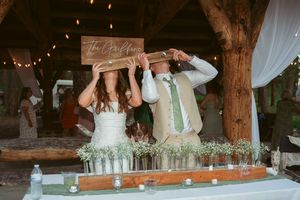Reception setup at a rustic barn wedding with wooden beams overhead and decorative lighting.