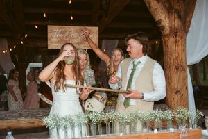 Newlyweds sharing drinks at their rustic barn reception with string lights overhead.