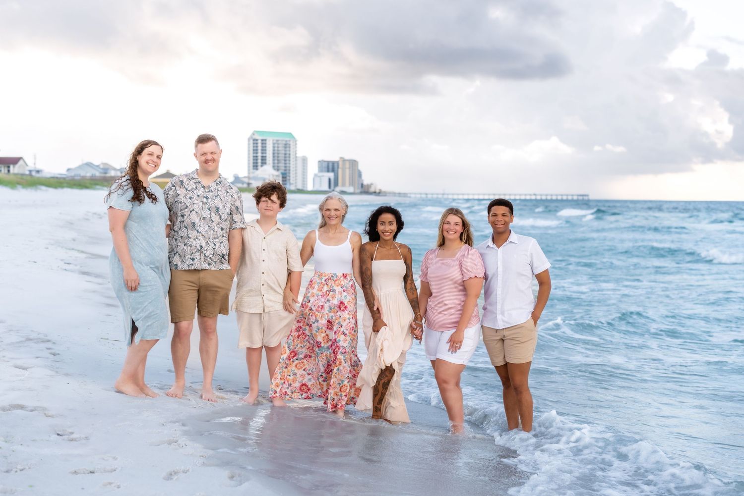 Group walks together along a scenic beach shoreline as waves roll in during a sunset photoshoot at the ocean.