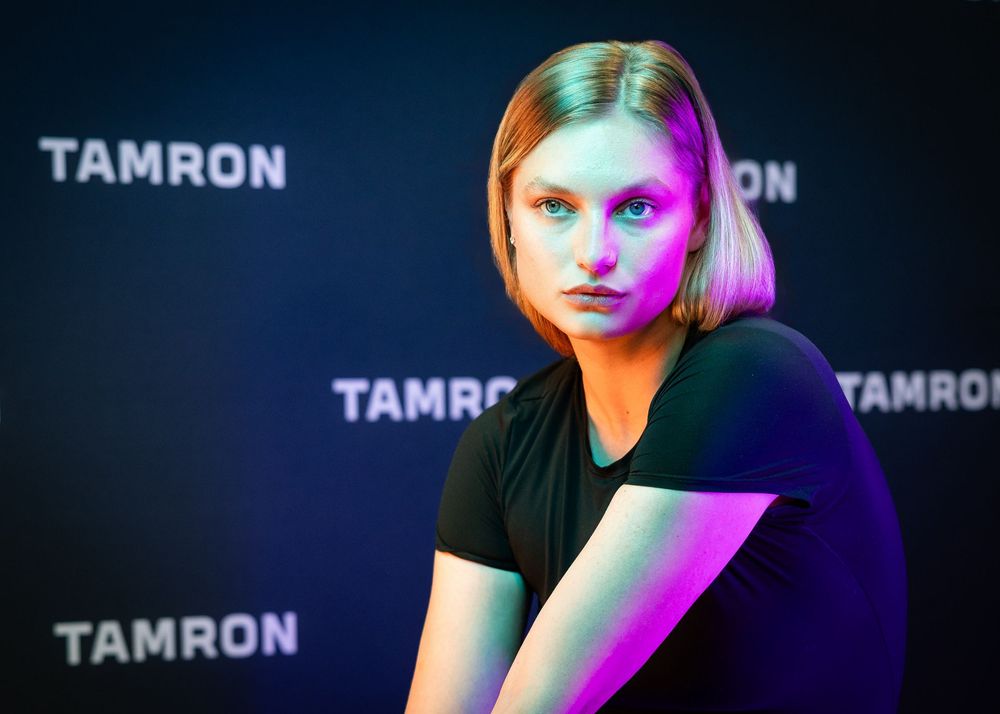 Artistic portrait with vibrant pink and green lighting effects against dark background.