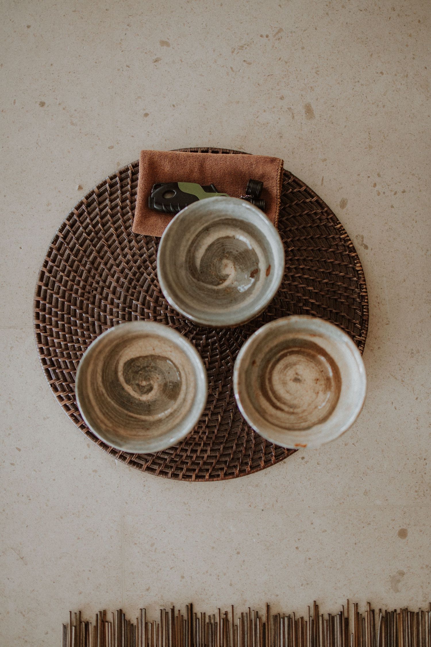Three ceramic bowls with swirled latte art patterns arranged on a woven rattan placemat viewed from above.