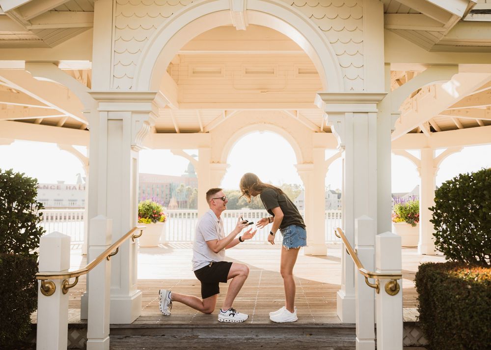 Young couple proposing at Disney Boardwalk during sunset at Sea Breeze Point gazebo. Cred: LexTakePix