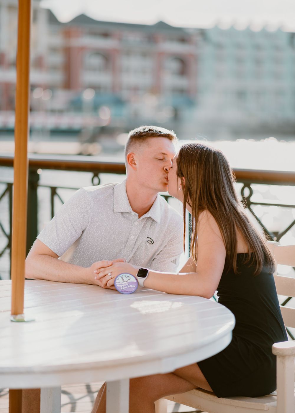 Young couple kissing at sunset at Disney Boardwalk during surprise proposal. Cred: LexTakePix