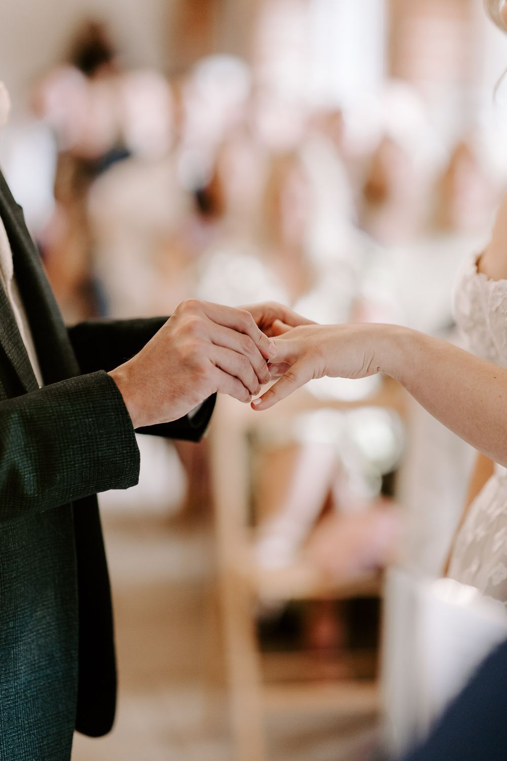 Close-up shots of two hands exchanging wedding rings during a marriage ceremony.