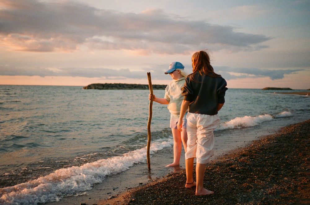 Scenic sunset beach panorama with gentle waves rolling onto the rocky shoreline as silhouettes walk along the coast.