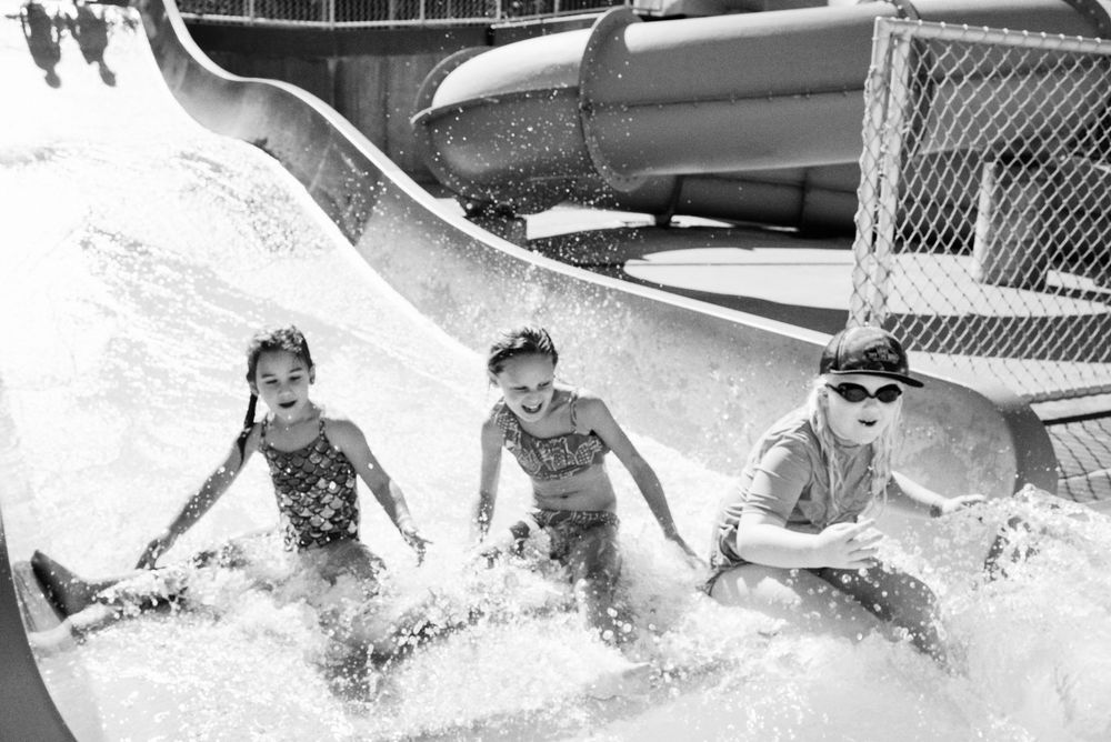 A series of black and white photos showing people enjoying water sports and surfing on ocean waves.