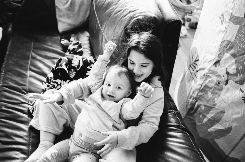 Black and white photo series showing tender moments between a parent and baby during playtime and cuddles.