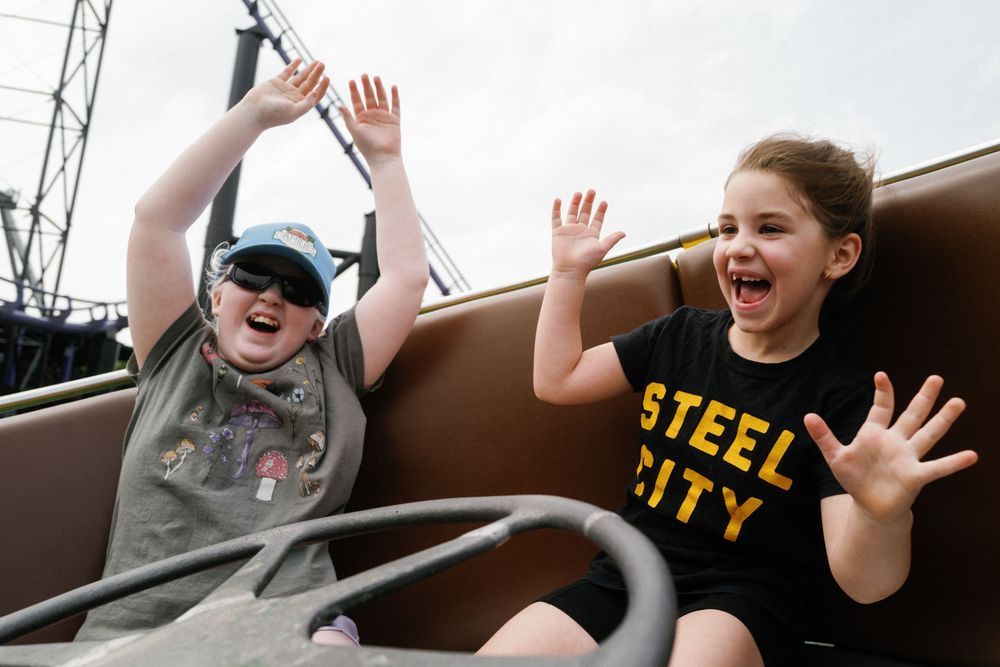 Two kids enjoying a thrilling ride at an amusement park showing joy and excitement.