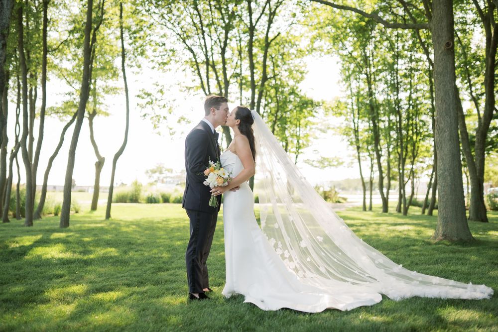 A romantic wedding scene unfolds in a sun-dappled wooded area.
