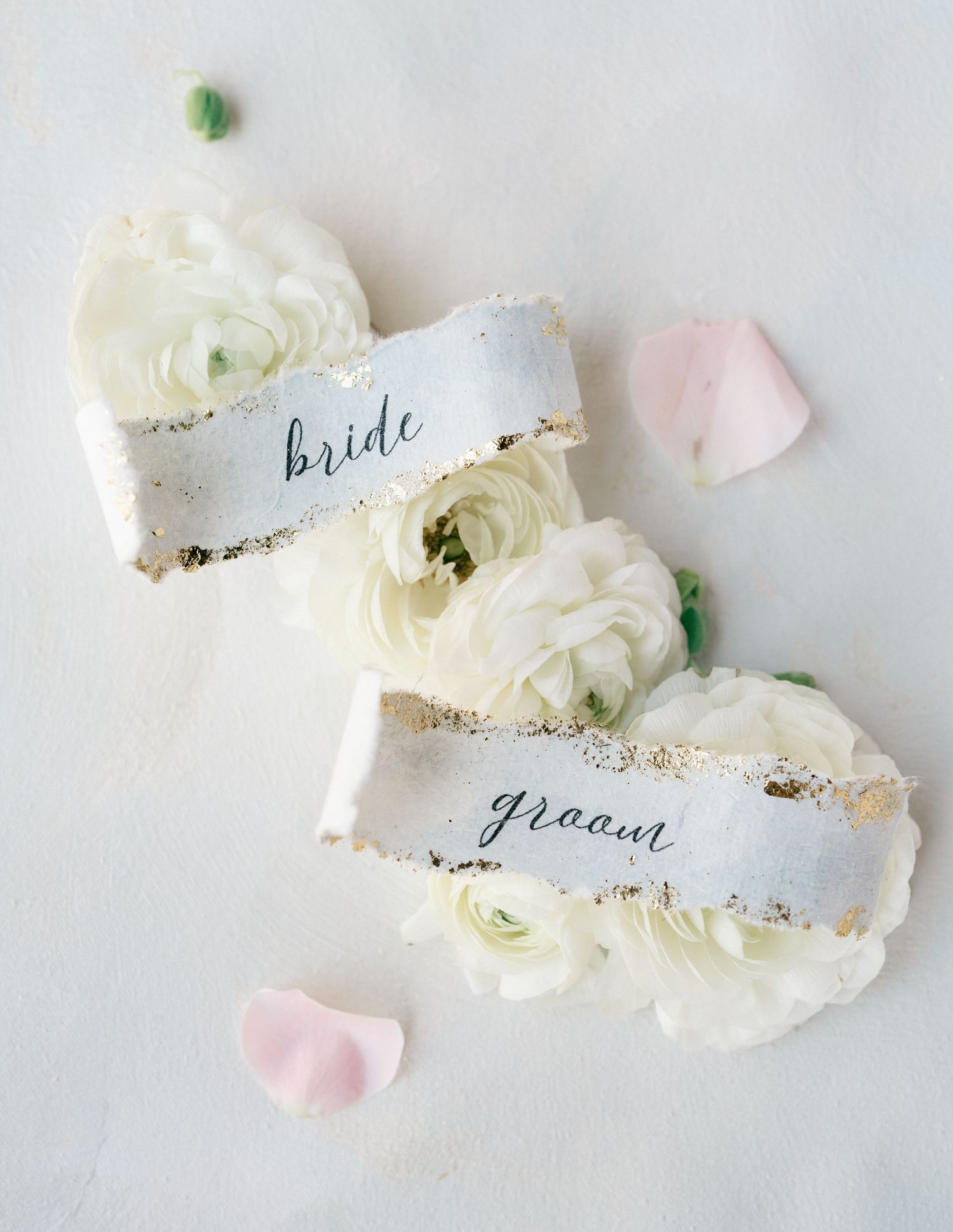 Elegant wedding invitation flat lay with pink roses, emerald green accents, wax seal, and ornate gold picture frame.