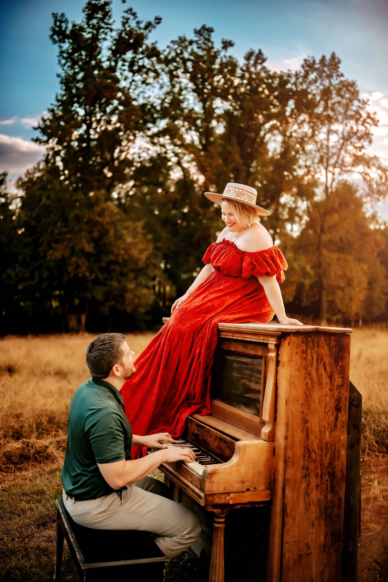 Parent and child share a joyful moment while sitting on a blanket in an autumn field during sunset.