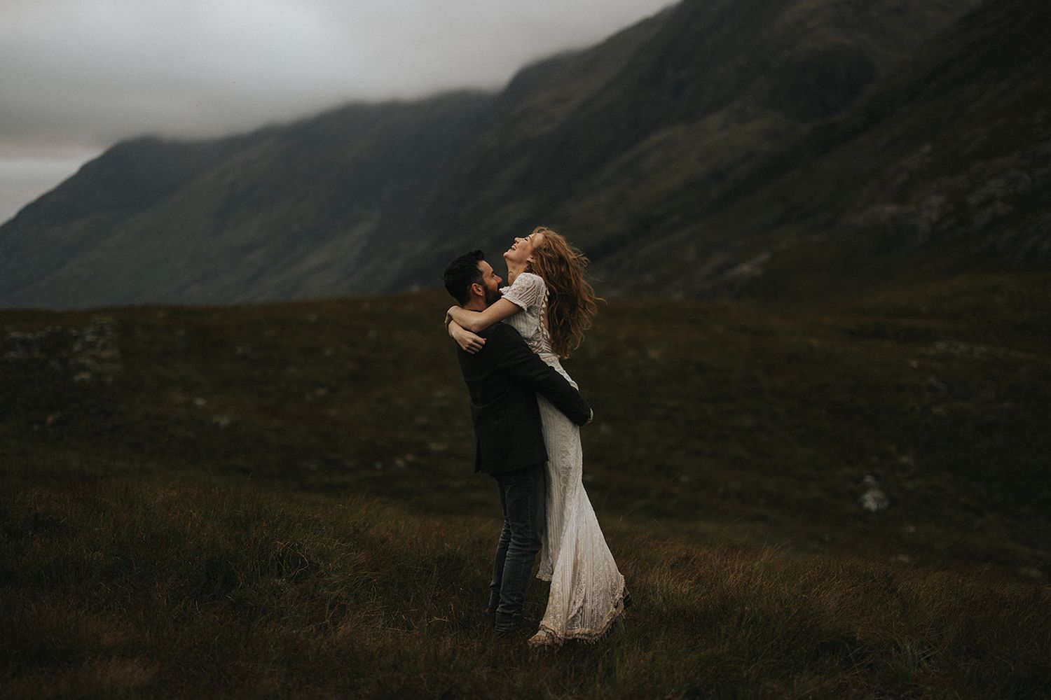 A romantic wedding couple embraces in an outdoor setting with natural lighting and elegant formal attire.