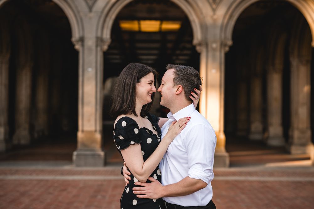 Romantic couple shares intimate moment under ornate stone archway.