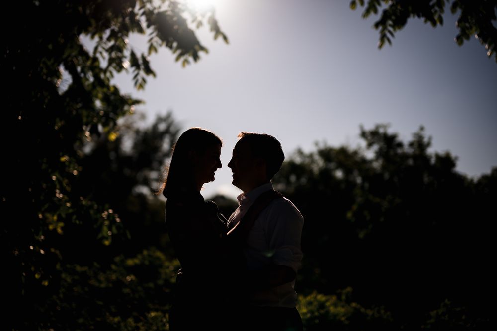Silhouetted figures against a bright sky with trees in the background.