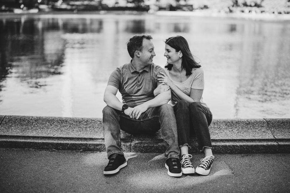 A couple sitting by a serene lake sharing an intimate moment.