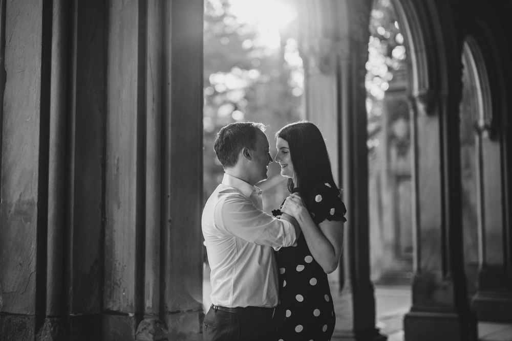 Black and white romantic engagement portrait under archway.