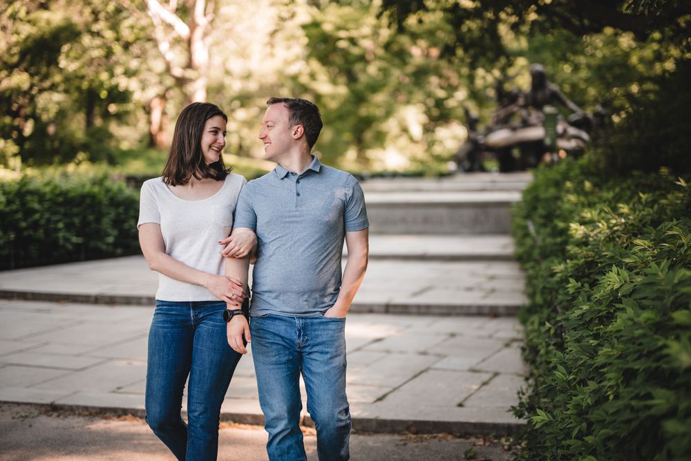 A couple walking together on a stone pathway surrounded by greenery.