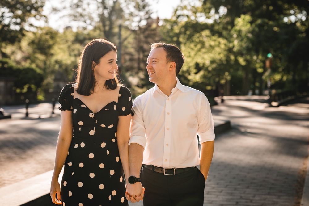 Couple walking together on a sunny path wearing polka dot dress and white shirt.