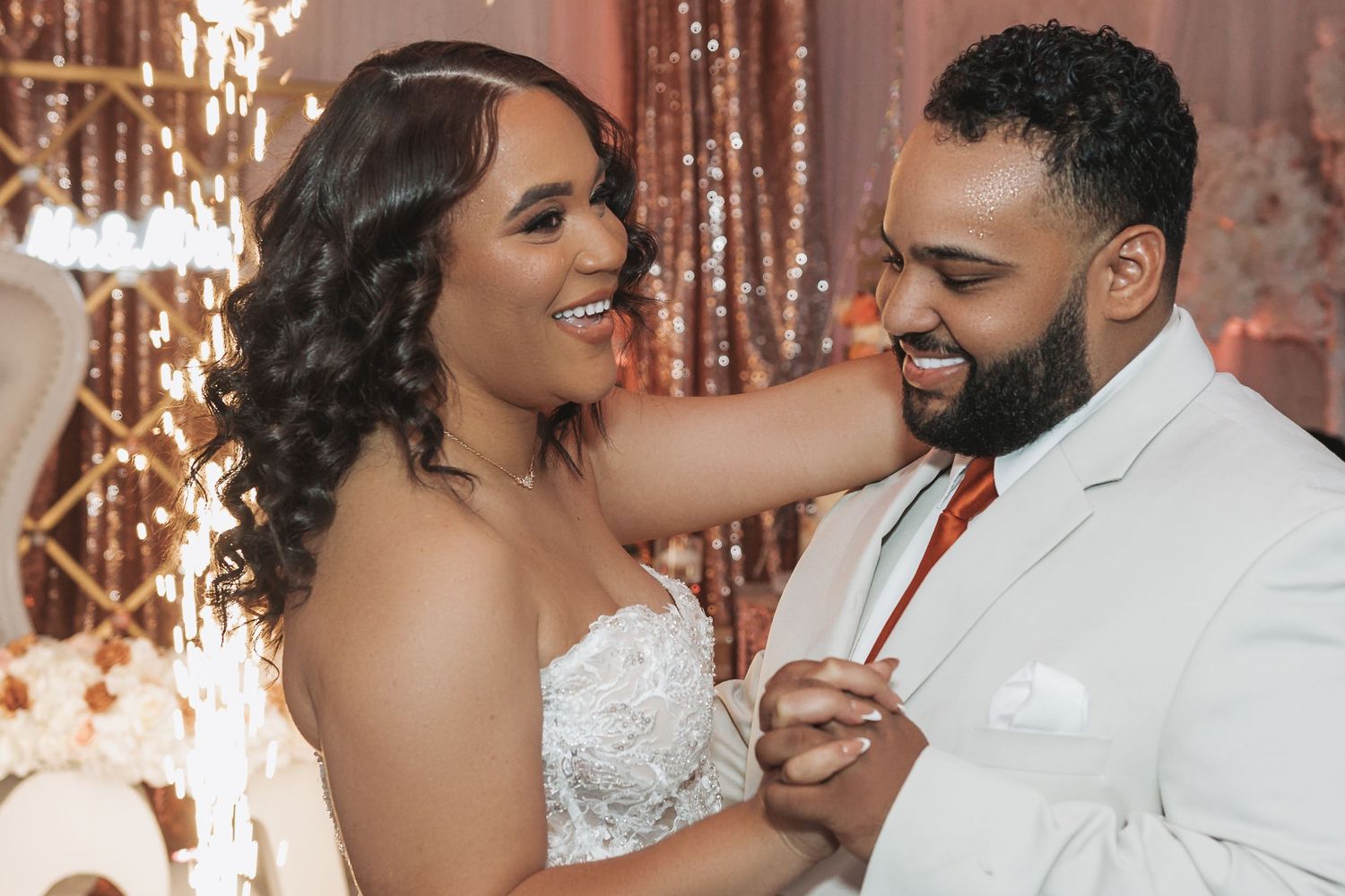 Happy couple shares an intimate moment while dancing and smiling at their wedding celebration.