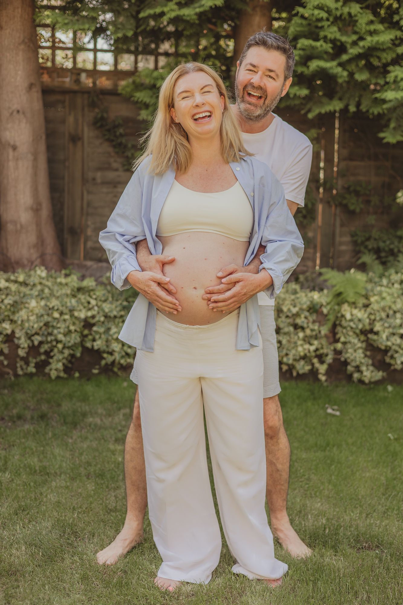 pregnancy / maternity photoshoot in Balham - husband and wife laughing and holding bump
