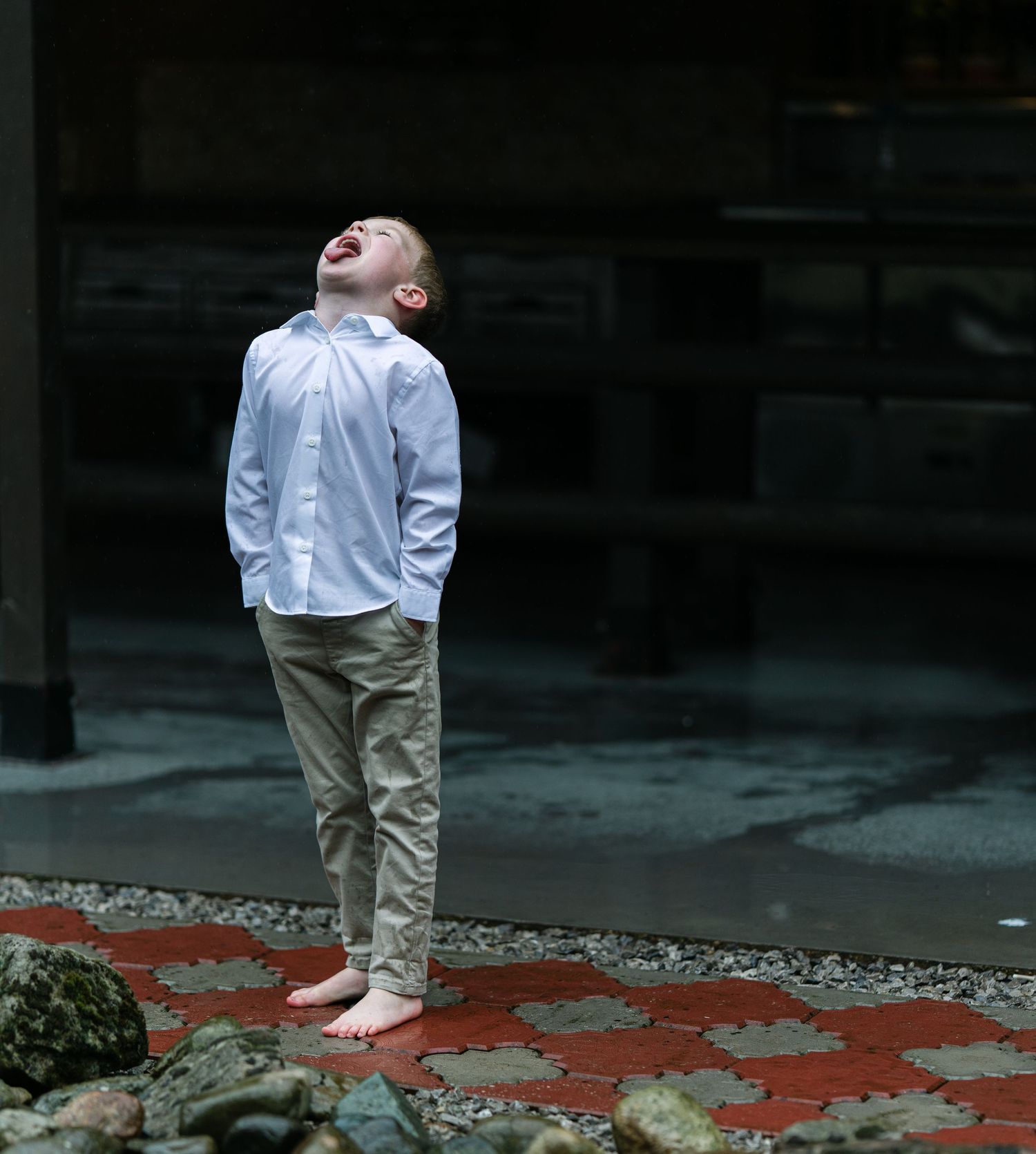 Person in white shirt and khaki pants stands on red pattern surface in dark moody setting.