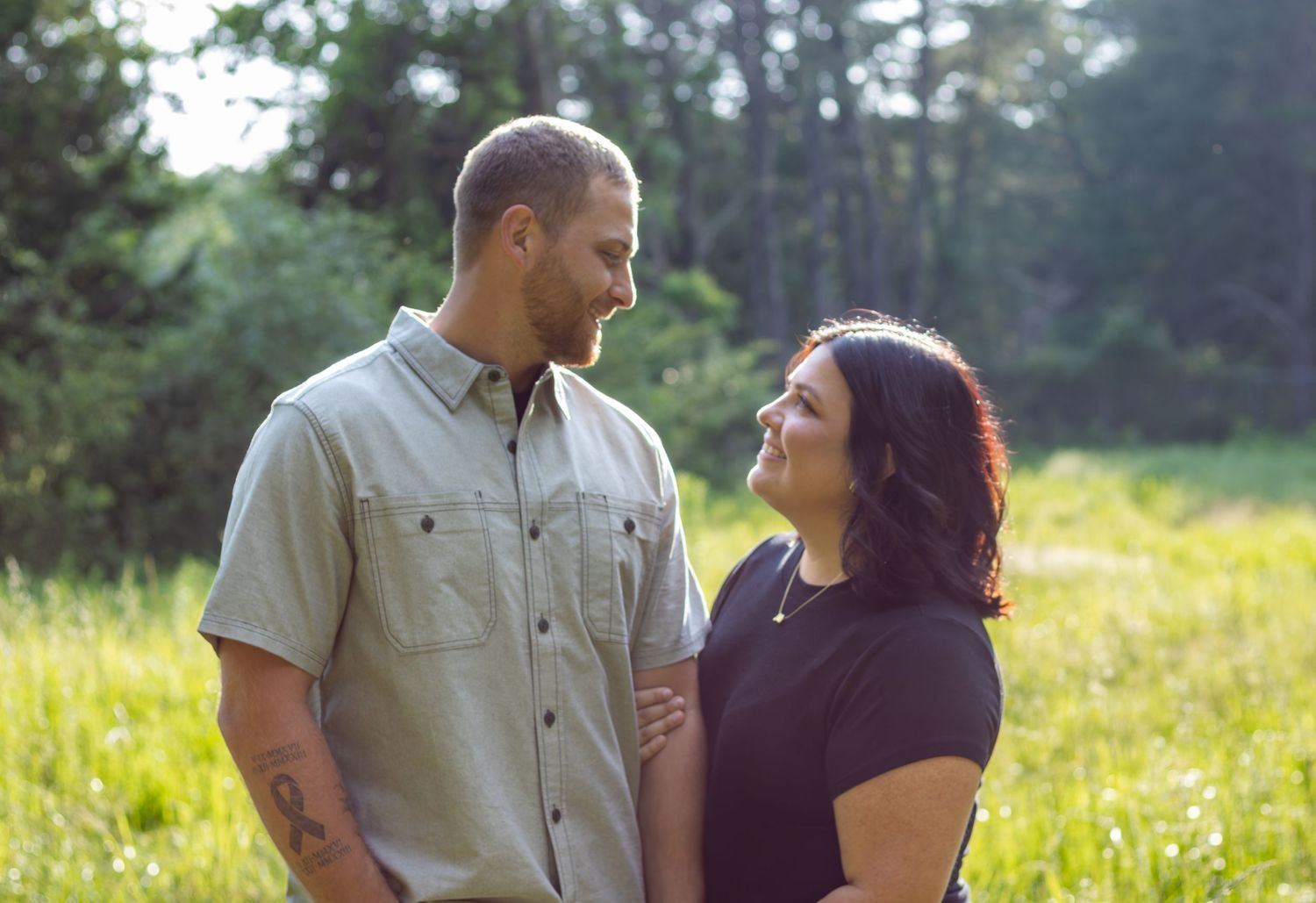 A couple enjoying a sunny day together in a field with wildflowers as they share a tender moment outdoors.