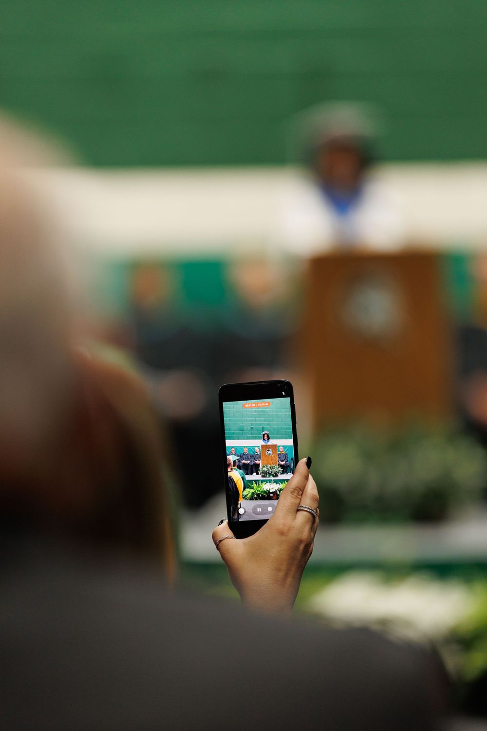A person takes a landscape photo on a smartphone of a grassy area outdoors on a clear day.