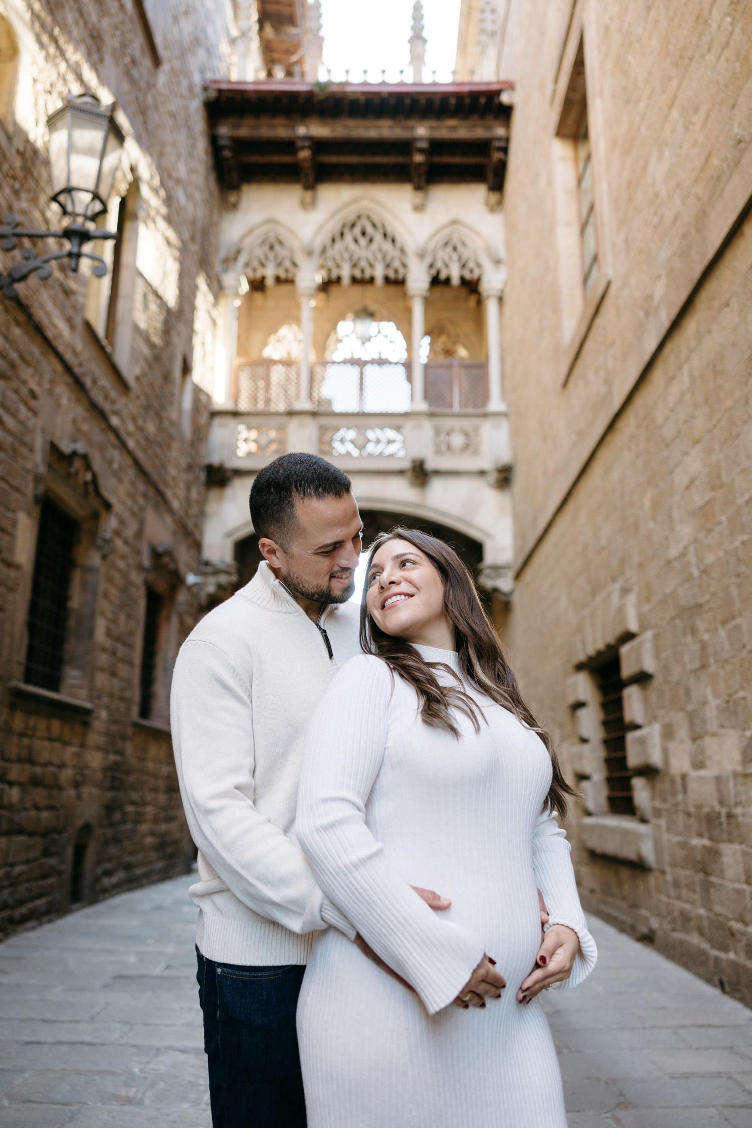 Romantic maternity photoshoot in a medieval stone alleyway with gothic architecture.