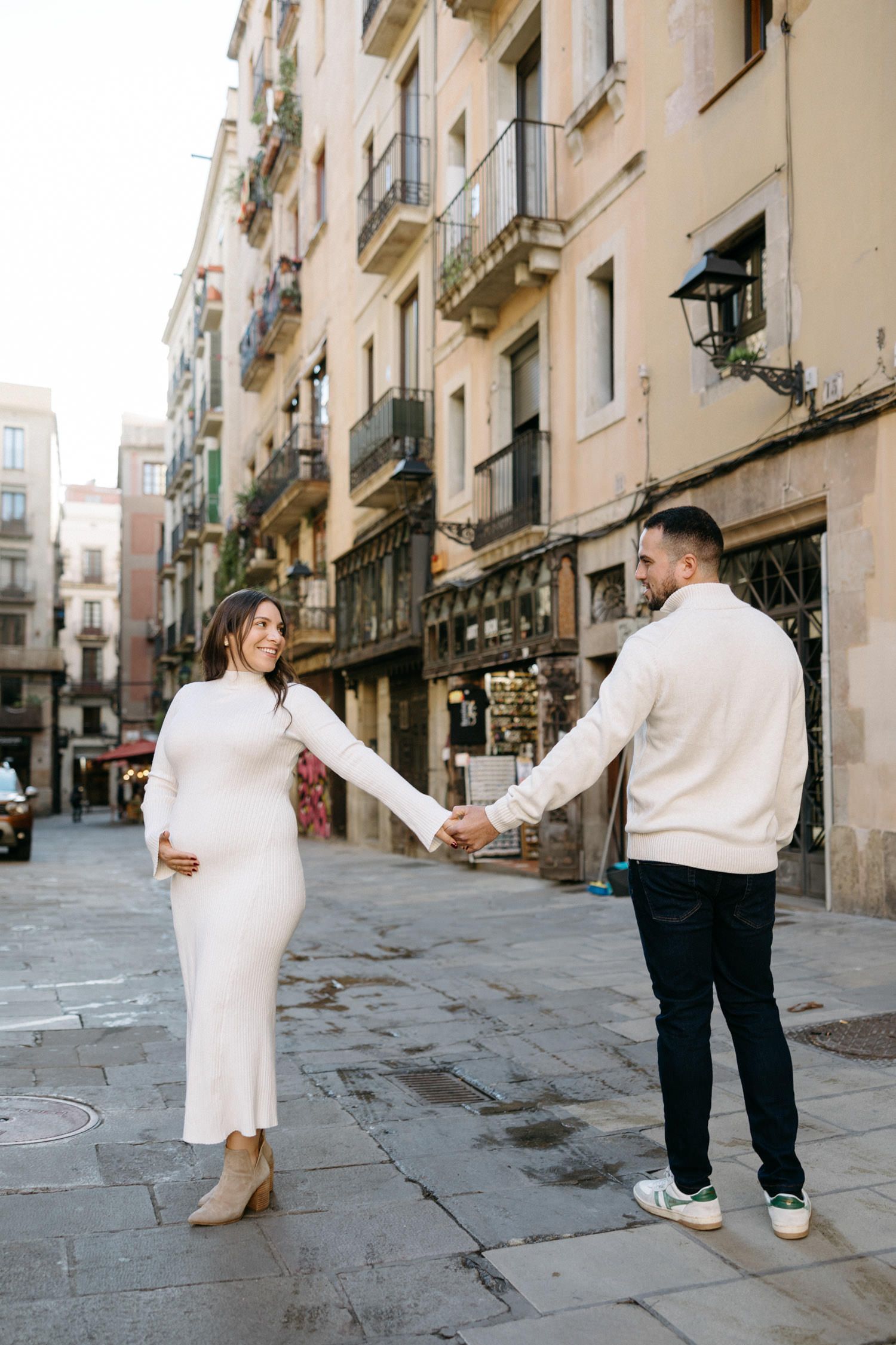 Couple dancing and twirling on cobblestone street in urban setting.