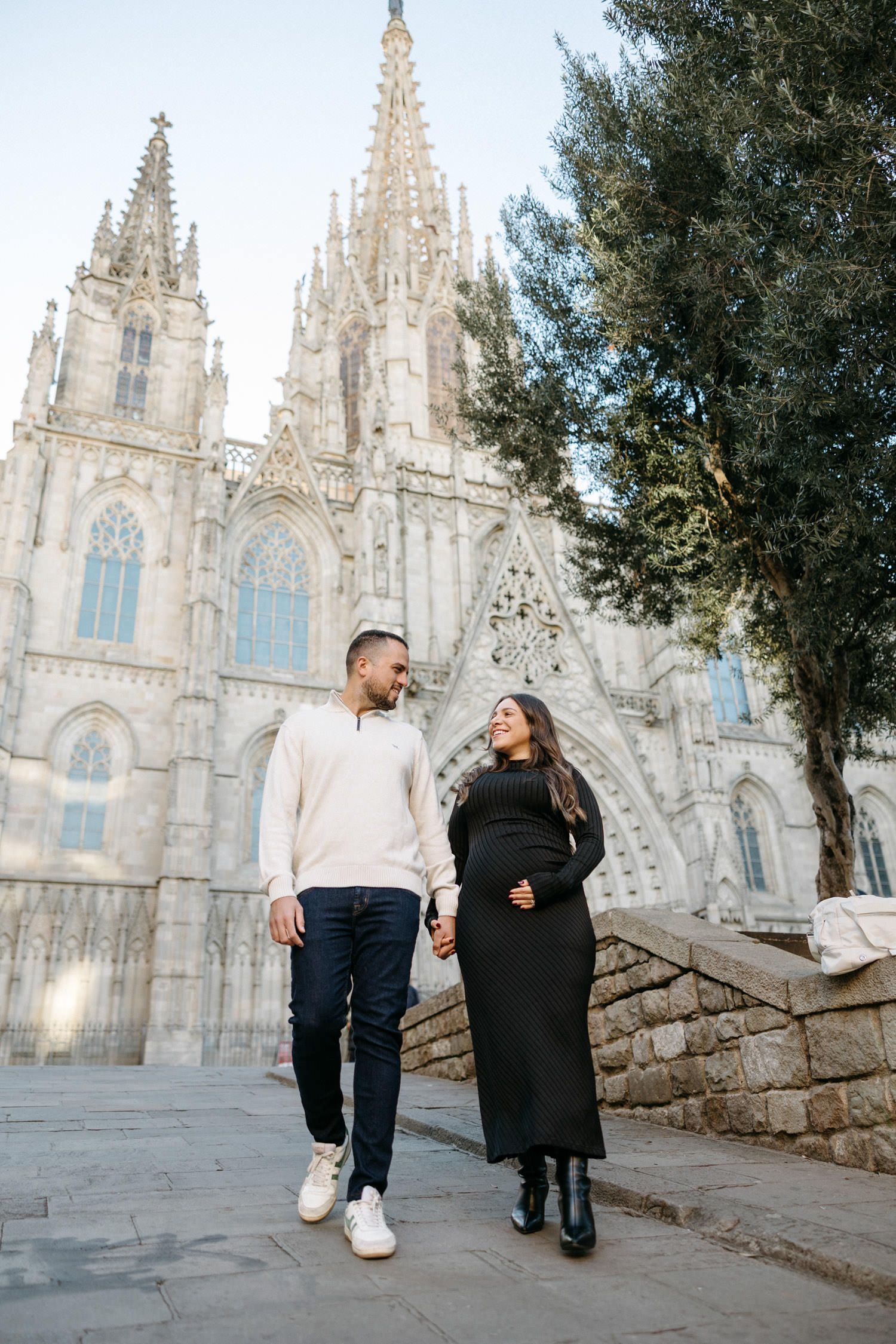 A couple shares an intimate moment in front of Barcelona Cathedral's ornate Gothic facade.