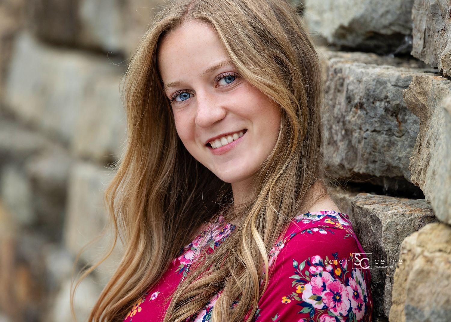 Professional portrait photo series showing someone in a vibrant pink floral dress against a rustic stone wall backdrop.