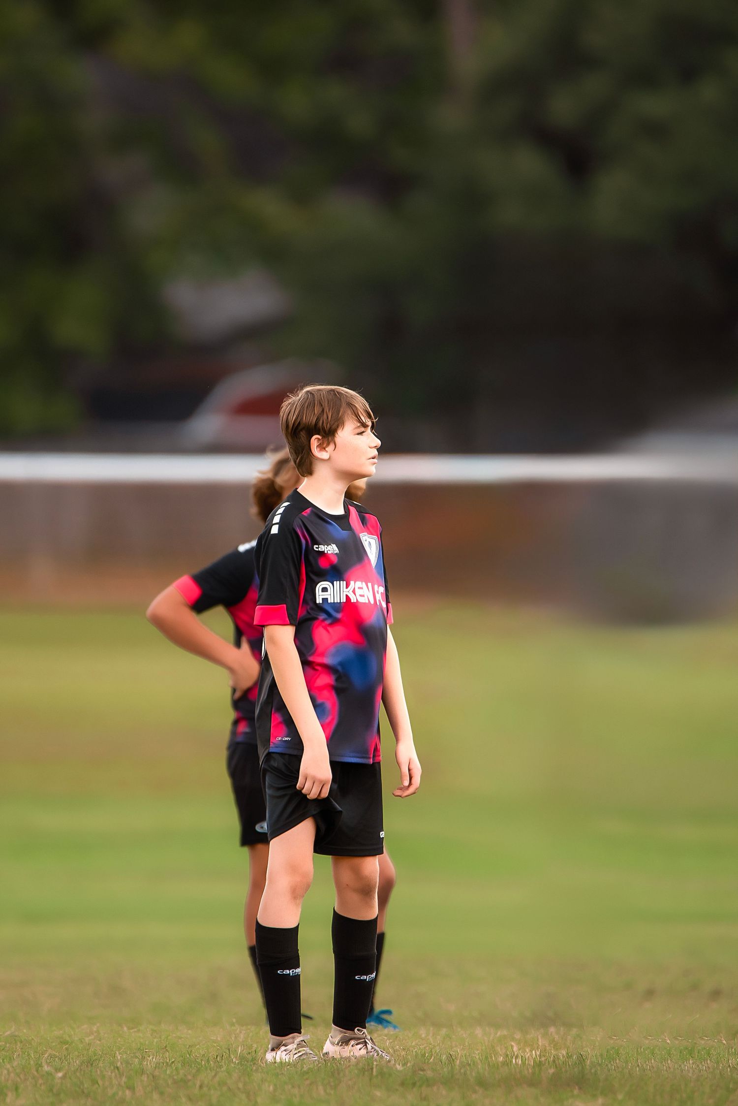 Soccer player kneeling on grass field while stretching and warming up during practice.