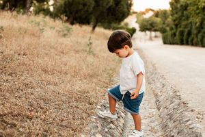 Child exploring nature path wearing casual summer outfit in evening light.