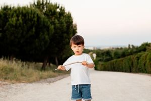 Young child in white t-shirt and denim shorts playing outdoors on a country path.