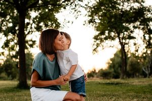 Intimate family moment shared outdoors during golden hour in a park setting.