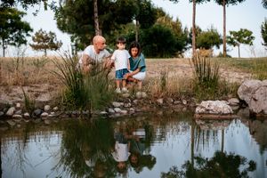 Family enjoying quality time together while fishing at a peaceful pond with reflections.