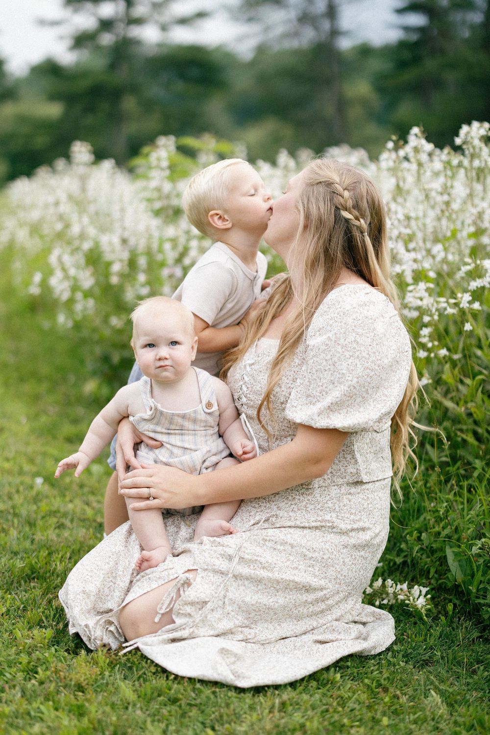 A heartwarming family moment captured in a field of white wildflowers on a sunny summer day.