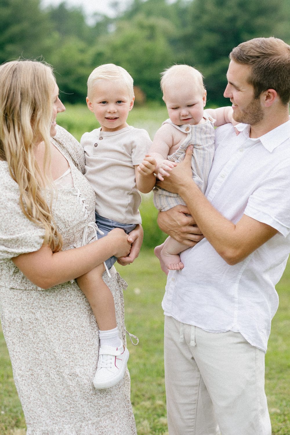 Series of tender moments in a meadow with people wearing white and cream colored outfits on a bright summer day.