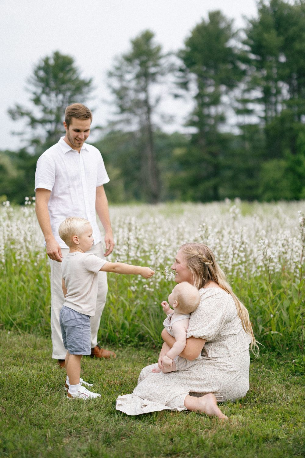 Happy moment with family playing together in a beautiful summer meadow filled with white wildflowers.