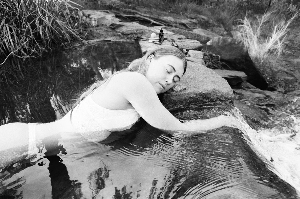 Feminine figure immersed in nature with floating florals – emotive branding shoot at Lesmurdie Falls near Perth