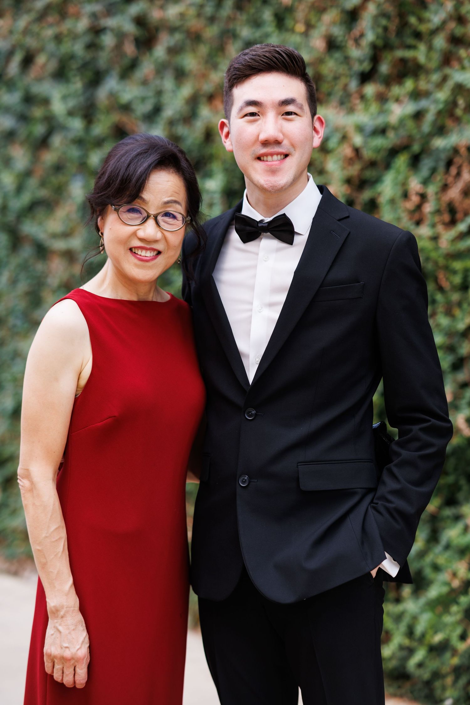 Groom posing with his mother for a family wedding photo outside