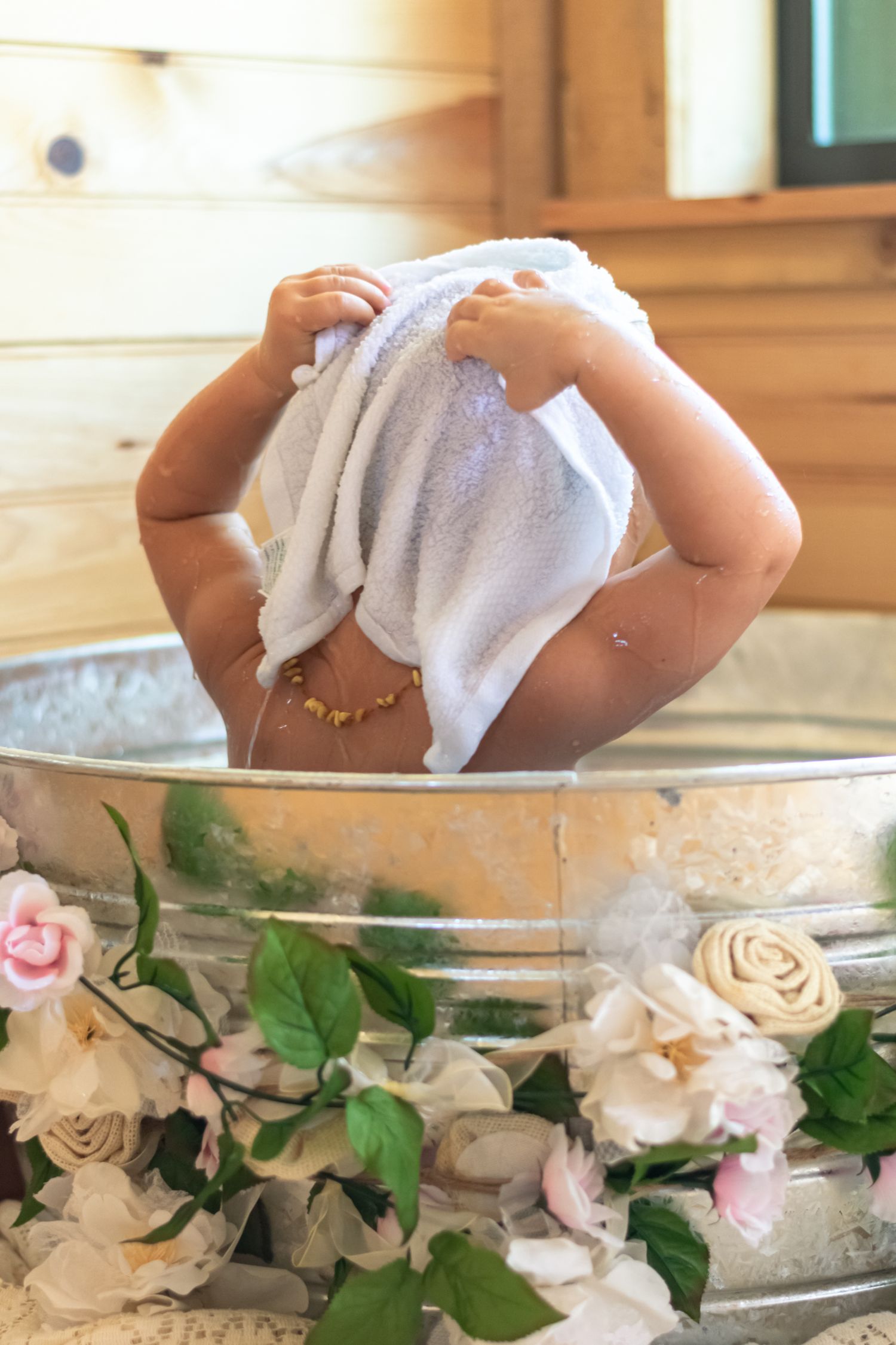 Baby taking a bath in vintage metal tub decorated with pink and white roses.