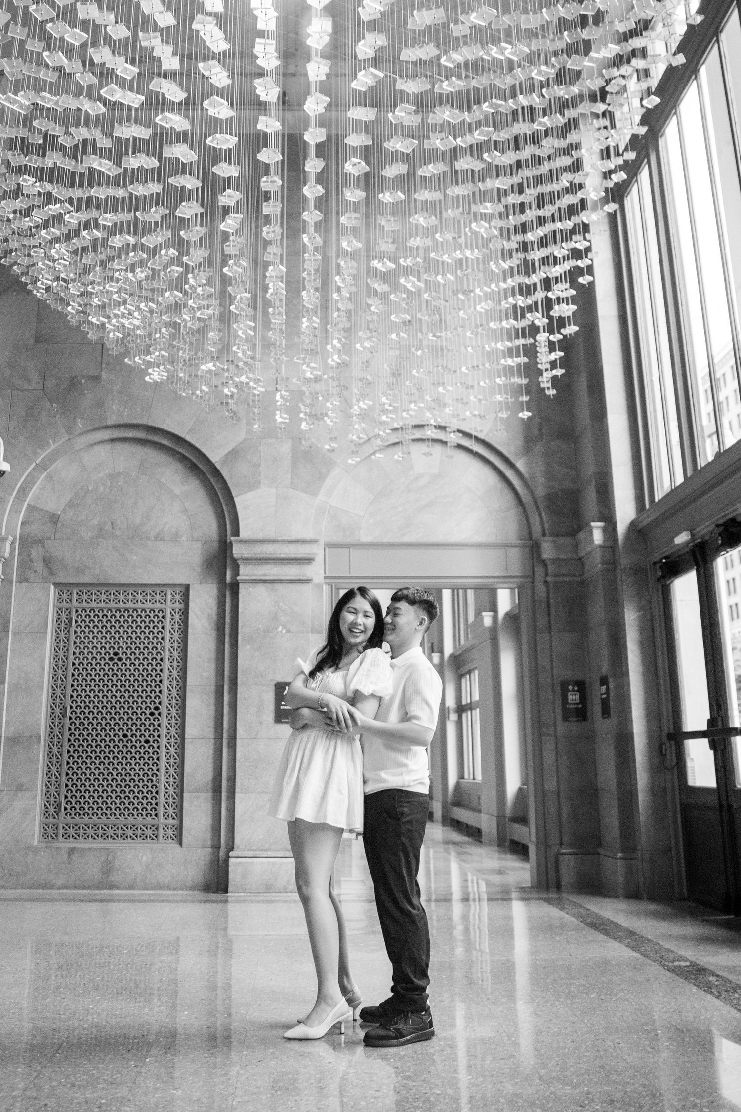 Four black and white photos show someone jumping gracefully beneath an ornate domed ceiling with hanging crystal decorations.