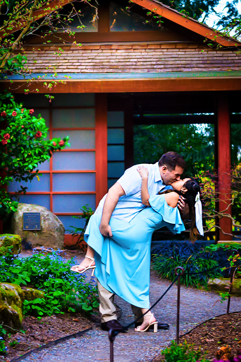 A romantic couple poses together in a series of photos at a Japanese garden walkway with red wood pergolas.