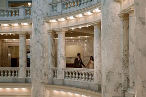 Panoramic view of an ornate marble interior with classical columns and balustrades in a historic government building.