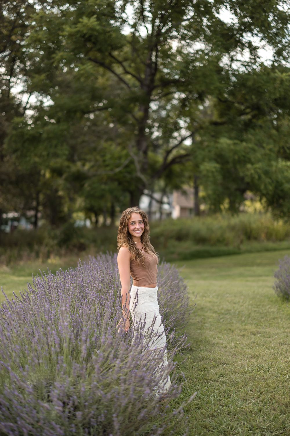 White dress flows elegantly among purple lavender bushes in a lush garden setting at golden hour.